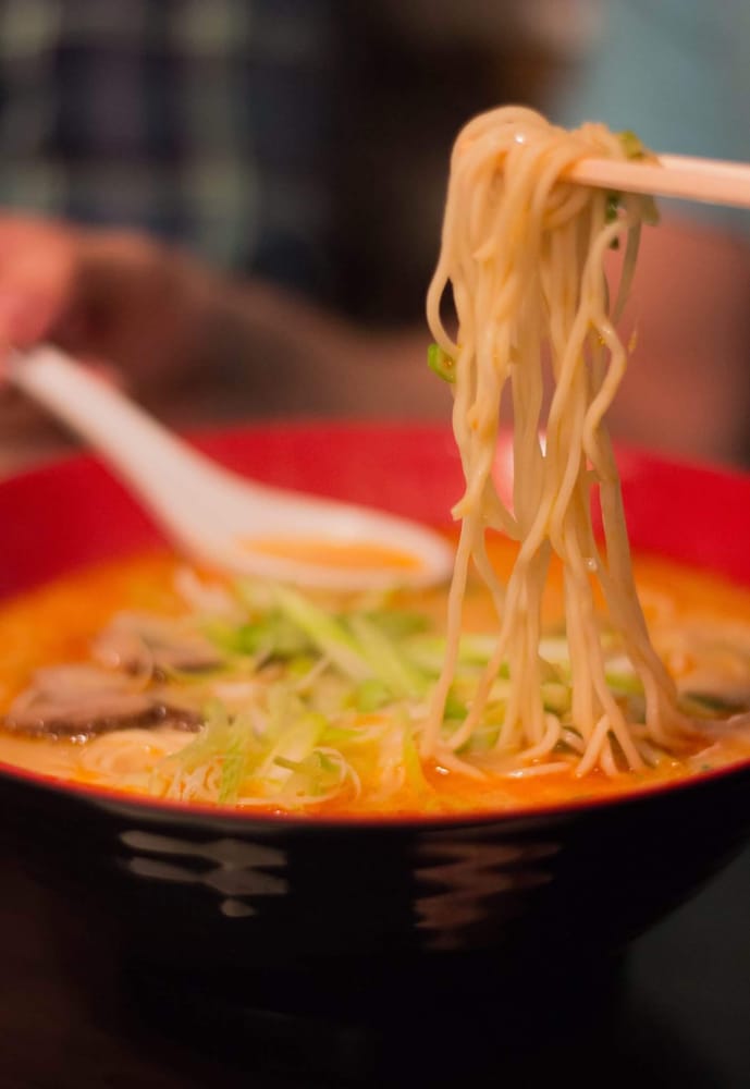 Ramen noodles lifted from the bowl with chopsticks